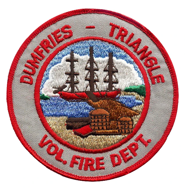 Embroidered patch with a ship, dock, and buildings. Red border and text reads: “DUMFRIES – TRIANGLE VOL. FIRE DEPT.” Blue sky and water in the background.